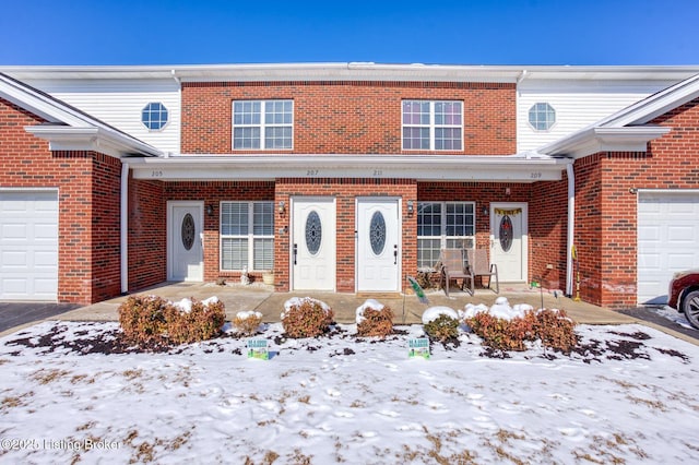 view of property featuring a garage, a porch, and brick siding