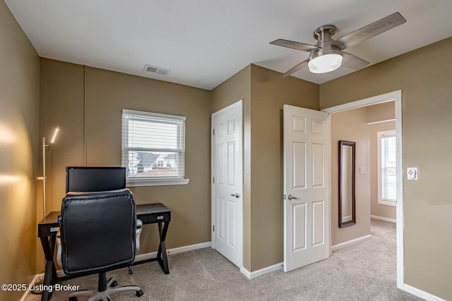 office area with baseboards, a ceiling fan, visible vents, and light colored carpet