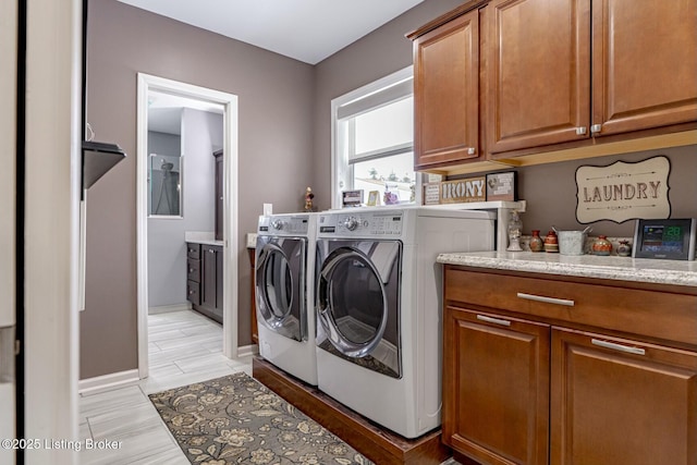 laundry room featuring cabinet space, baseboards, and separate washer and dryer