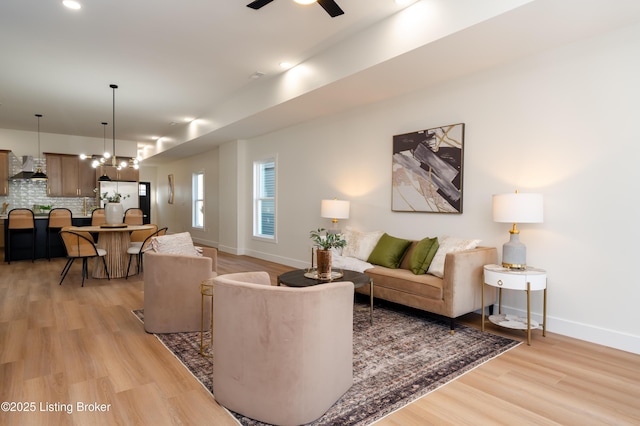 living area with baseboards, light wood-style floors, and ceiling fan