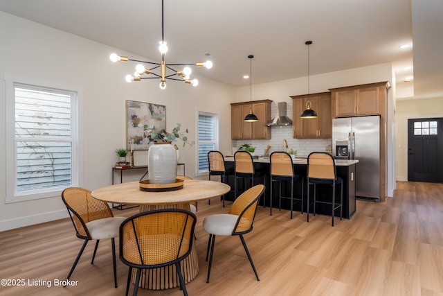 dining room featuring an inviting chandelier, baseboards, and light wood-type flooring