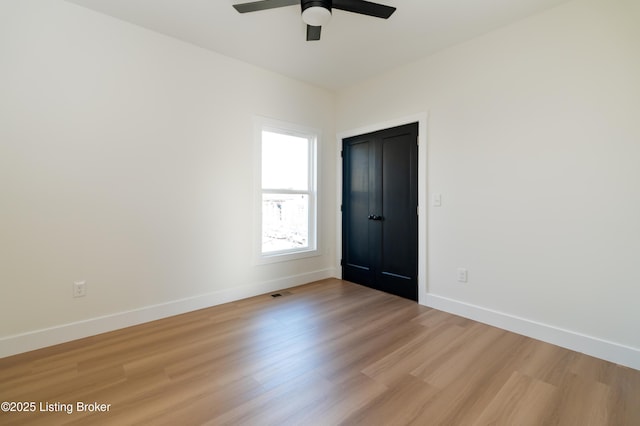 unfurnished room featuring light wood-style flooring, baseboards, visible vents, and ceiling fan