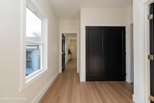 corridor featuring baseboards and light wood finished floors