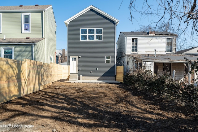 rear view of house with entry steps and fence