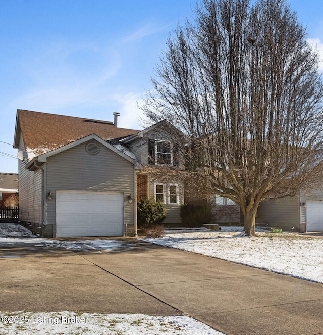 traditional-style home with concrete driveway, roof with shingles, and an attached garage