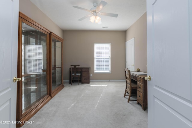 office space featuring light carpet, a ceiling fan, and baseboards