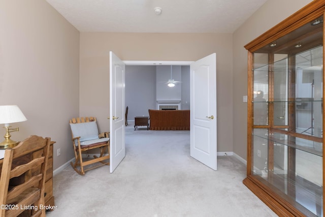 hall featuring baseboards and light colored carpet