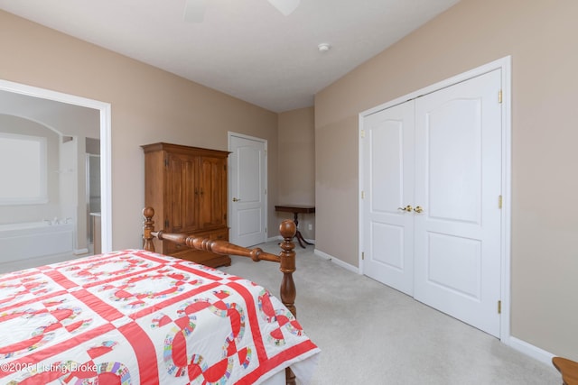 carpeted bedroom featuring ensuite bath, baseboards, ceiling fan, and a closet