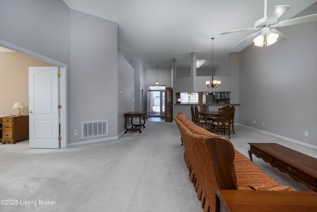 living area featuring baseboards, a high ceiling, visible vents, and light colored carpet