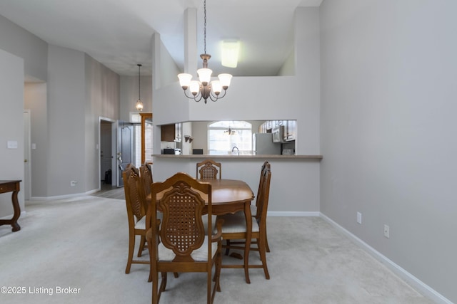 dining room featuring carpet, a high ceiling, baseboards, and a notable chandelier