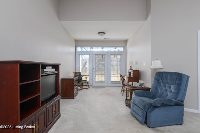 living area with baseboards and light colored carpet