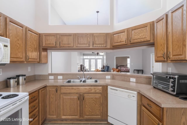 kitchen featuring white appliances, a toaster, a peninsula, light countertops, and a sink