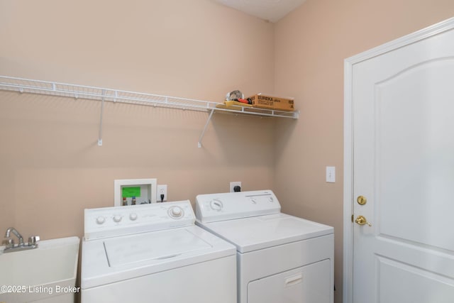 washroom featuring laundry area, separate washer and dryer, and a sink