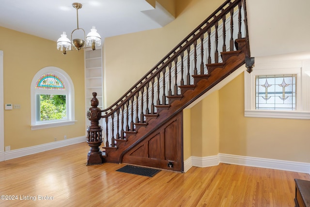 staircase featuring a notable chandelier, baseboards, and wood finished floors