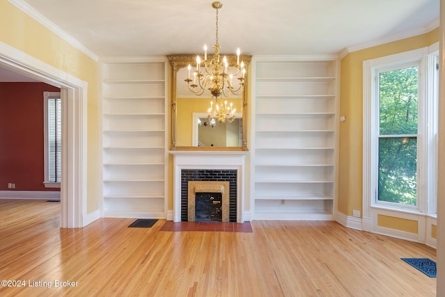 unfurnished living room with a healthy amount of sunlight, built in shelves, a fireplace, and wood finished floors