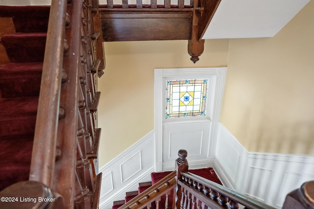 stairway with beamed ceiling and wainscoting