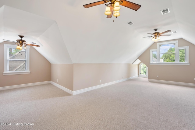 additional living space featuring light colored carpet, visible vents, lofted ceiling, and baseboards