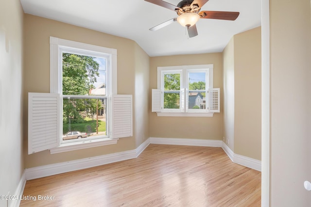 unfurnished room with ceiling fan, lofted ceiling, light wood-style flooring, and baseboards