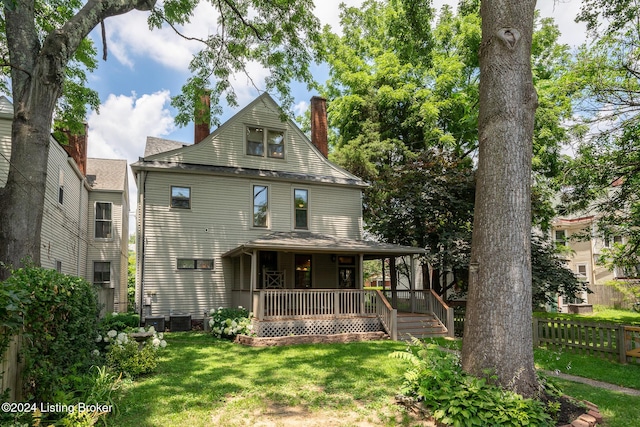 back of house with covered porch, a yard, central AC unit, and fence