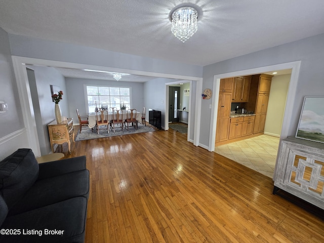 living room featuring light wood-style flooring, a chandelier, and baseboards