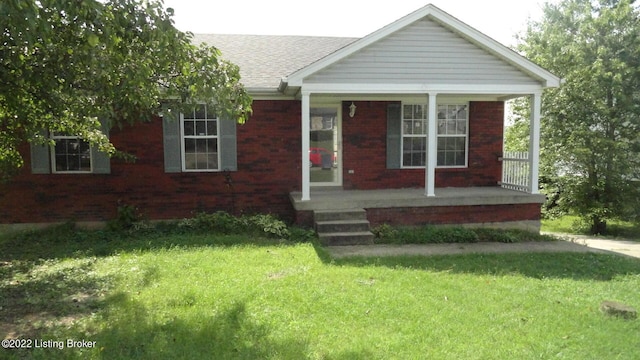 view of front facade featuring a shingled roof, covered porch, brick siding, and a front lawn