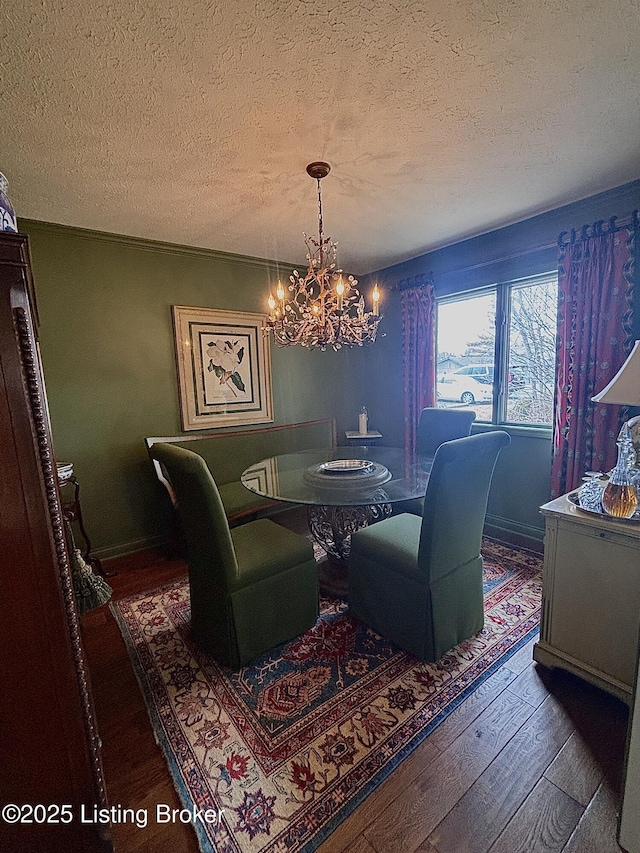 dining space featuring dark wood finished floors, a textured ceiling, and an inviting chandelier