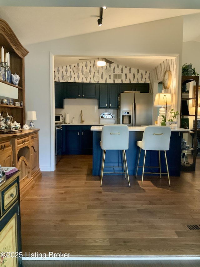 kitchen with lofted ceiling, a kitchen breakfast bar, a peninsula, stainless steel appliances, and light countertops