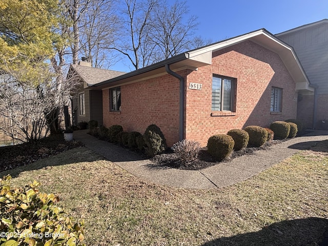 view of side of property with brick siding and a chimney