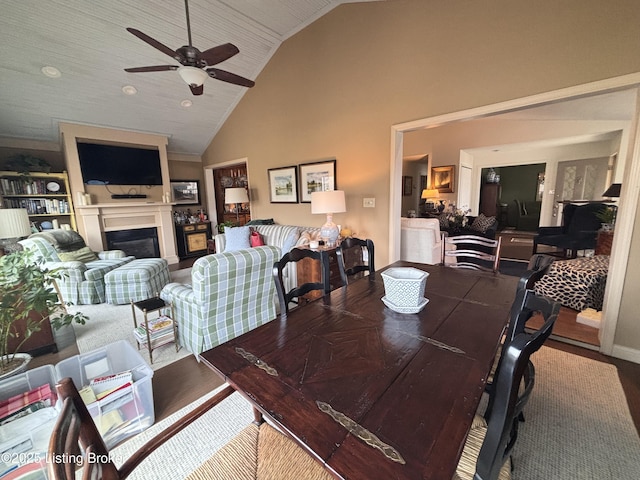 dining area featuring ceiling fan, high vaulted ceiling, and a fireplace