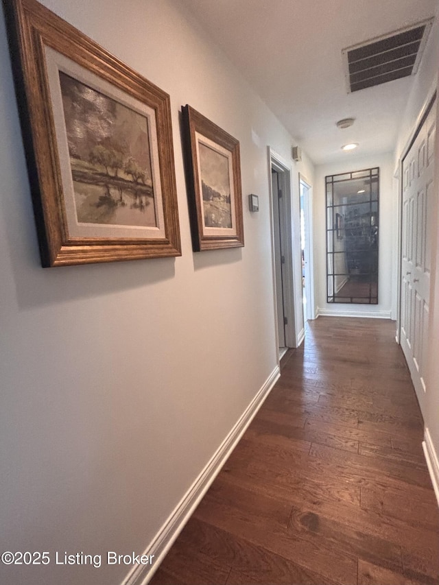 corridor with dark wood-type flooring, visible vents, and baseboards