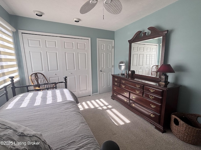 bedroom featuring ceiling fan, a textured ceiling, two closets, and light colored carpet