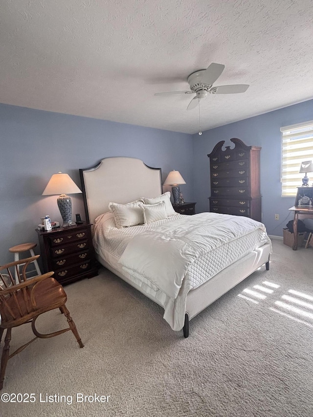 carpeted bedroom featuring ceiling fan and a textured ceiling