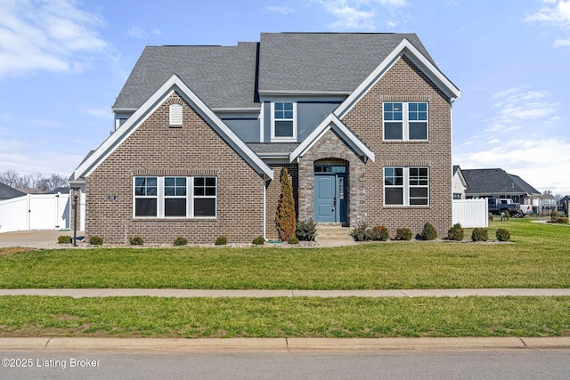 view of front of property with a front yard, a gate, brick siding, and fence