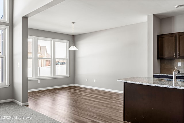 unfurnished dining area featuring dark wood-type flooring, a sink, and baseboards