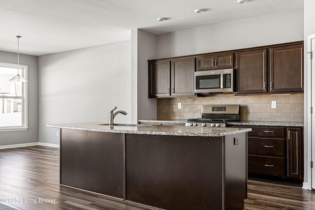 kitchen with stainless steel appliances, a sink, dark brown cabinetry, and tasteful backsplash