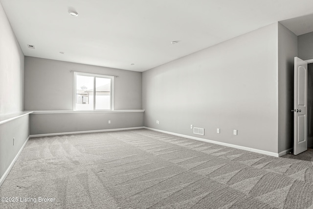 carpeted spare room with visible vents and baseboards