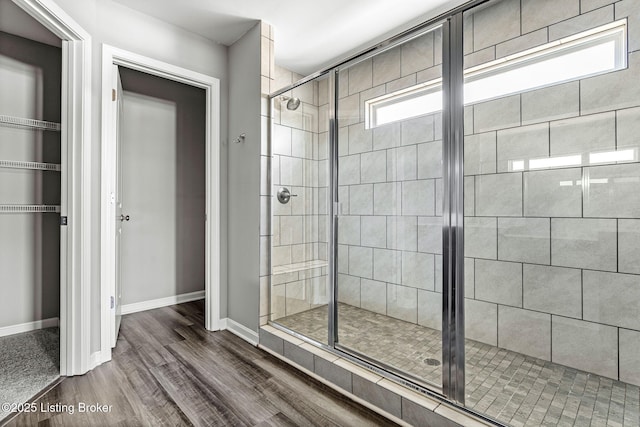 full bath with a stall shower, baseboards, and wood finished floors