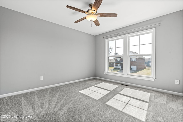 empty room with carpet, visible vents, ceiling fan, and baseboards