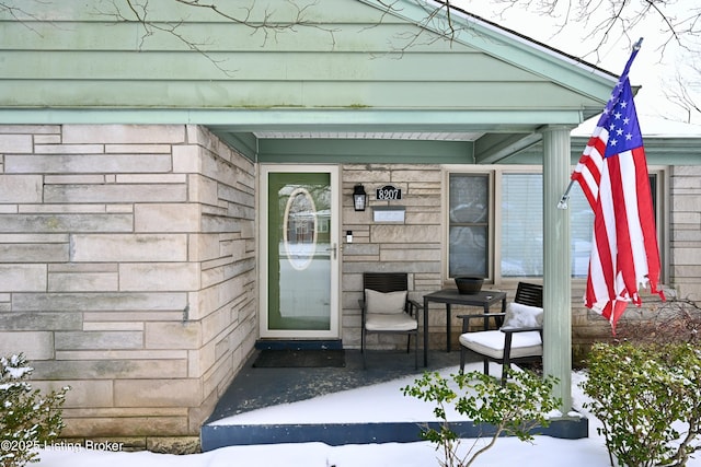 snow covered property entrance featuring stone siding