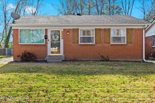 bungalow-style home featuring entry steps, a front lawn, a shingled roof, and brick siding