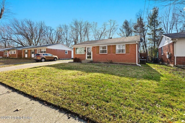 view of front facade with concrete driveway, brick siding, a front yard, and cooling unit