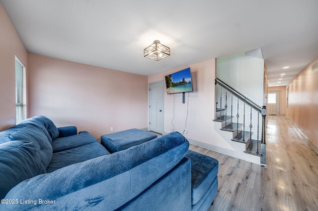 living area featuring baseboards, stairway, wood finished floors, and a healthy amount of sunlight