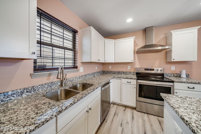 kitchen featuring stainless steel appliances, white cabinetry, a sink, and wall chimney range hood