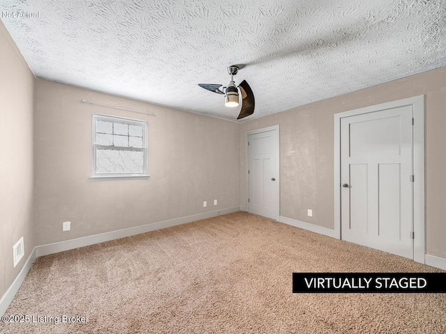 unfurnished bedroom featuring a ceiling fan, carpet, visible vents, and a textured ceiling