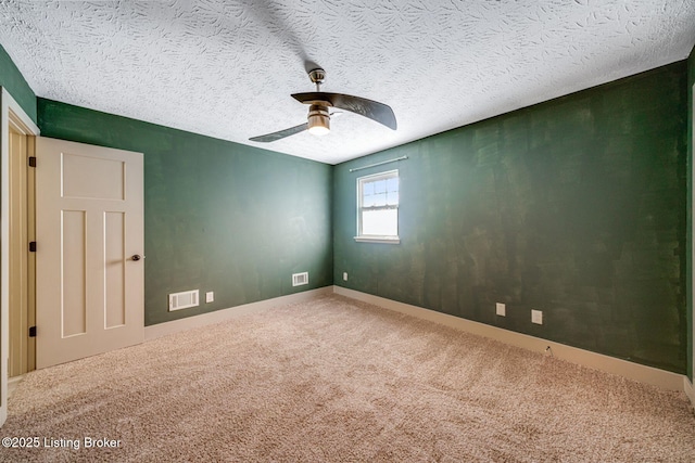 carpeted spare room featuring visible vents, ceiling fan, a textured ceiling, and baseboards