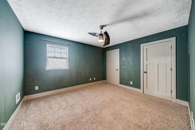 unfurnished bedroom with carpet, visible vents, ceiling fan, a textured ceiling, and baseboards