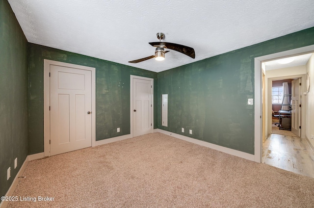 unfurnished bedroom featuring a textured ceiling, carpet floors, a ceiling fan, and baseboards