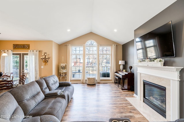 living area with light wood finished floors, a high end fireplace, vaulted ceiling, french doors, and recessed lighting