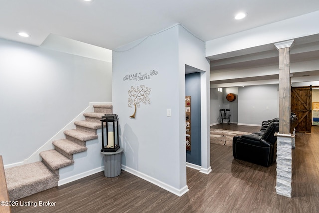 interior space with a barn door, wood finished floors, and baseboards