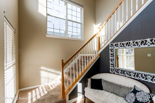 stairs with carpet floors, a high ceiling, and baseboards